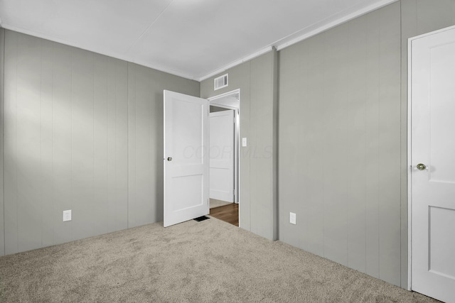 unfurnished bedroom with dark colored carpet and wooden walls