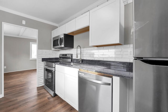 kitchen with appliances with stainless steel finishes, white cabinetry, ornamental molding, and sink