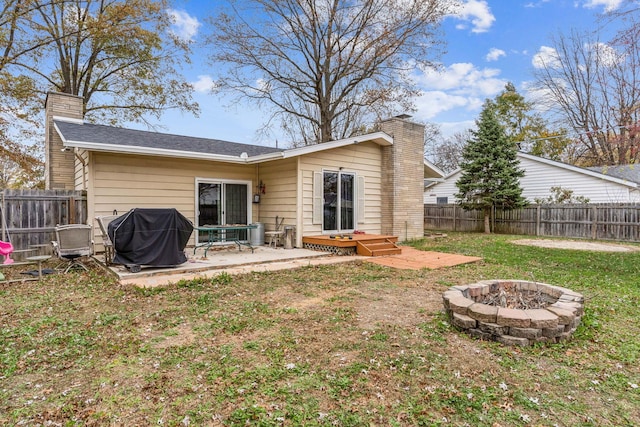 back of house with a lawn, a fire pit, and a patio