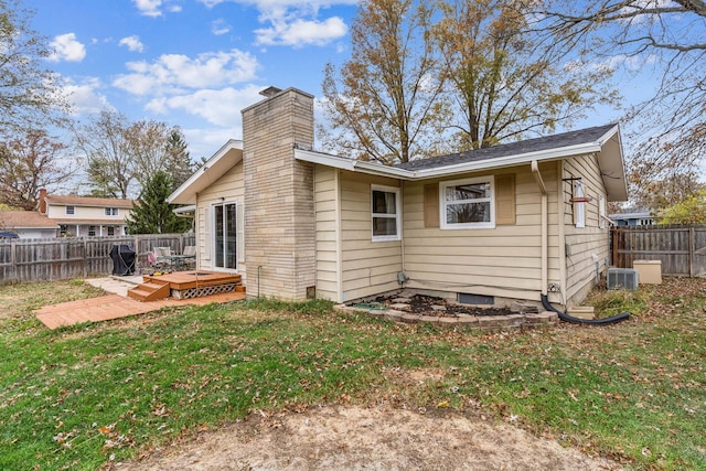 rear view of property featuring central AC unit, a yard, and a wooden deck