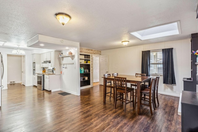 dining area with a textured ceiling, dark hardwood / wood-style flooring, and a skylight