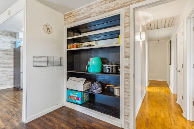 room details with stainless steel fridge, built in shelves, wooden walls, and hardwood / wood-style floors