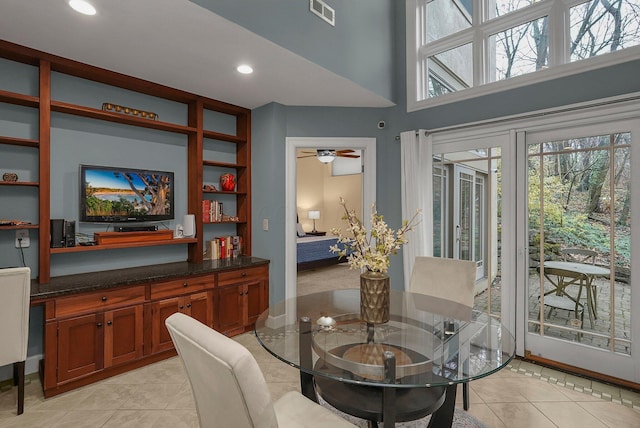 tiled dining area with a high ceiling and ceiling fan