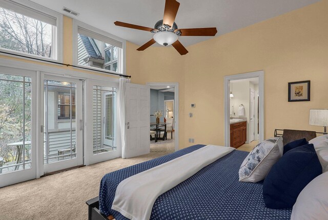 bedroom featuring light carpet, ceiling fan, access to exterior, a towering ceiling, and connected bathroom