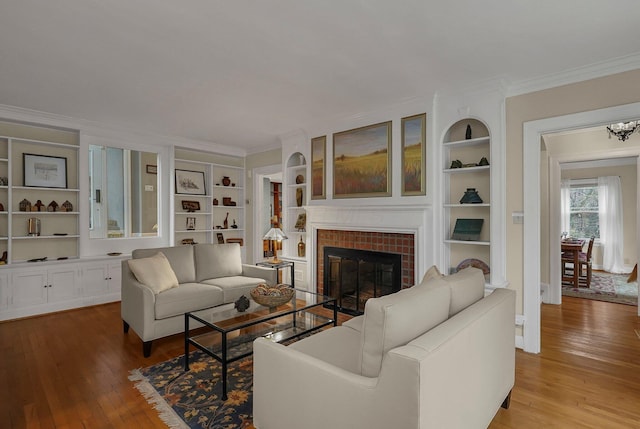 296 Walhalla Rd, Columbus, OH 43202 - living area with wood-type flooring, crown molding, built in shelves, a brick fireplace, and a chandelier