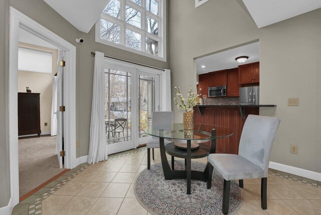 dining room with light tile patterned floors and a high ceiling