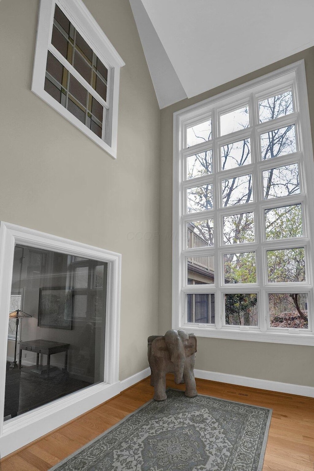 living area with light wood-type flooring, vaulted ceiling, and a wealth of natural light