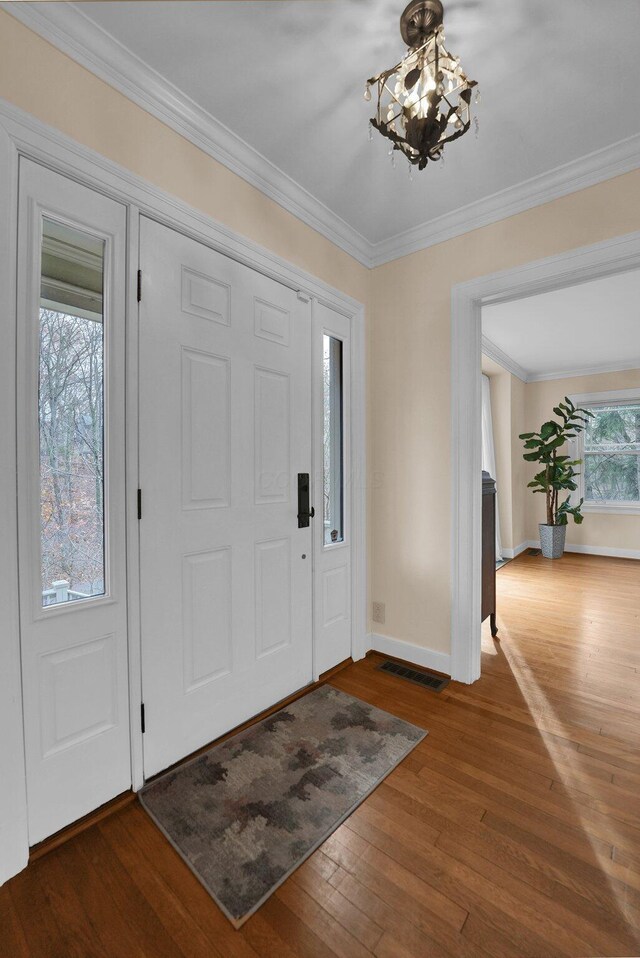 entryway featuring an inviting chandelier, dark wood-type flooring, and ornamental molding