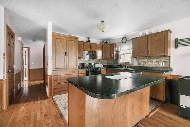 kitchen featuring appliances with stainless steel finishes, a center island, wooden walls, and light hardwood / wood-style flooring