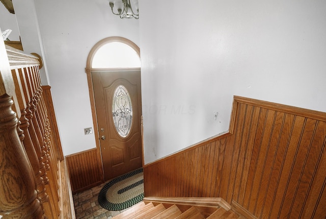 foyer entrance featuring wooden walls and an inviting chandelier