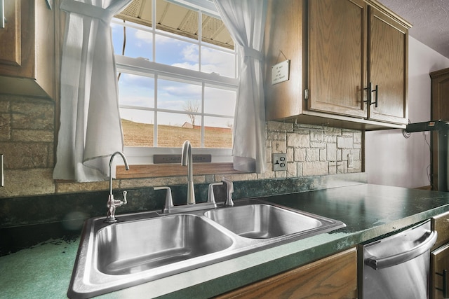 kitchen featuring stainless steel dishwasher, sink, and tasteful backsplash