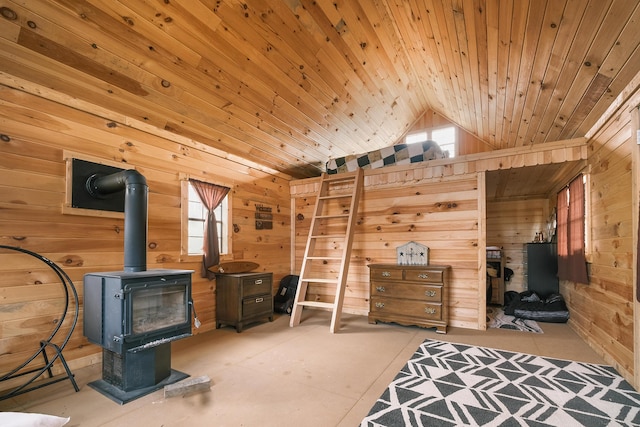 interior space featuring multiple windows, wooden walls, vaulted ceiling, and a wood stove