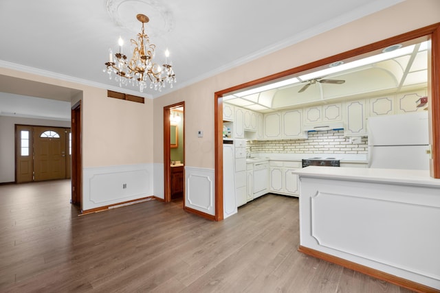 kitchen with white appliances, hanging light fixtures, white cabinetry, and light wood-type flooring