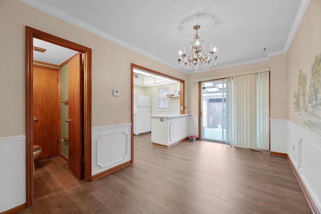 unfurnished dining area featuring ornamental molding, an inviting chandelier, and hardwood / wood-style flooring