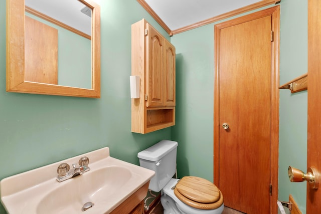 bathroom with toilet, ornamental molding, and vanity