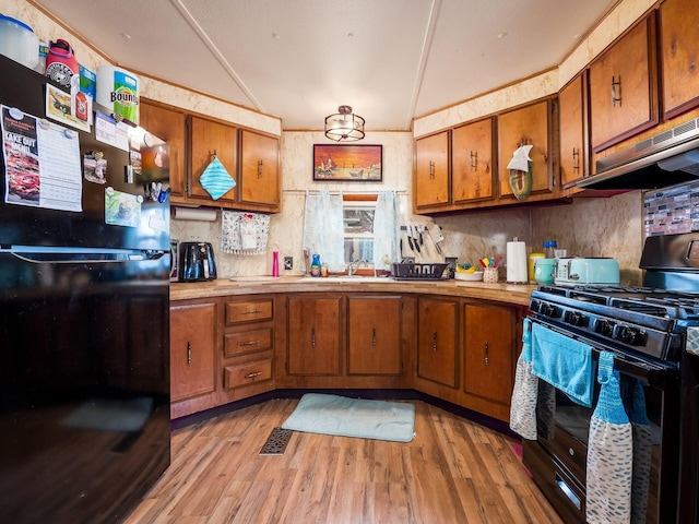 kitchen featuring decorative backsplash, ventilation hood, light hardwood / wood-style floors, and black appliances