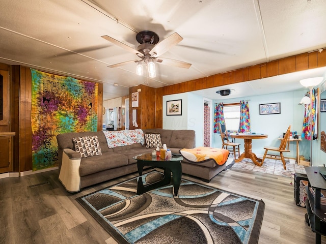 living room with hardwood / wood-style flooring, ceiling fan, and wooden walls