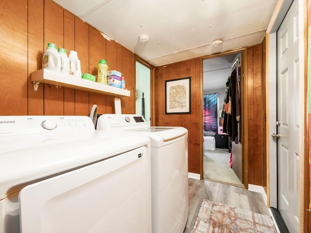 laundry area featuring wooden walls, light hardwood / wood-style flooring, and independent washer and dryer