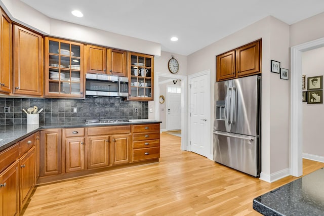 kitchen with appliances with stainless steel finishes, light wood-type flooring, and decorative backsplash