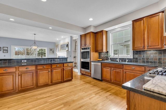 kitchen featuring appliances with stainless steel finishes, decorative light fixtures, light hardwood / wood-style floors, and backsplash