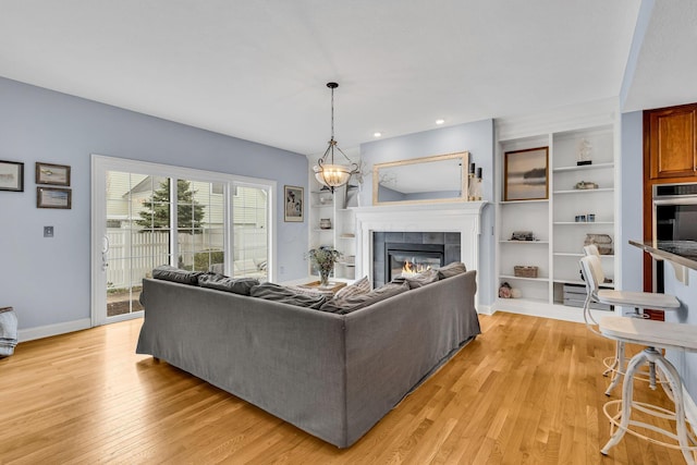 living room with a tiled fireplace and light wood-type flooring