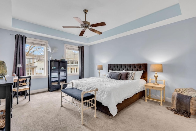 carpeted bedroom featuring a raised ceiling and ceiling fan