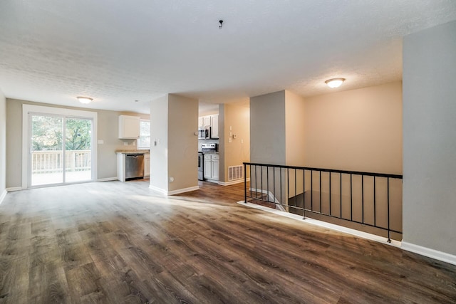 unfurnished living room featuring a textured ceiling and dark hardwood / wood-style floors