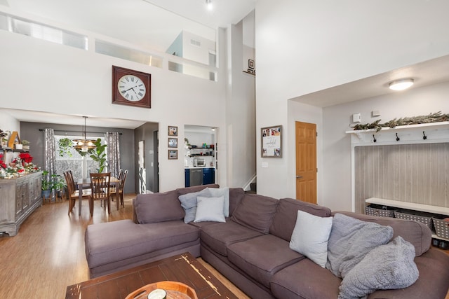 living room with a notable chandelier, wood-type flooring, and a high ceiling