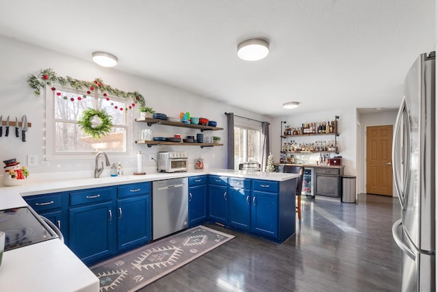 kitchen featuring kitchen peninsula, appliances with stainless steel finishes, blue cabinets, and a wealth of natural light