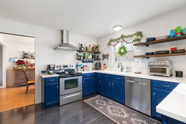 kitchen featuring blue cabinets, sink, wall chimney exhaust hood, dark hardwood / wood-style floors, and appliances with stainless steel finishes