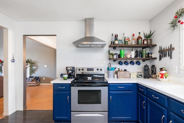 kitchen with stainless steel range with electric stovetop, wall chimney exhaust hood, dark hardwood / wood-style flooring, and blue cabinets