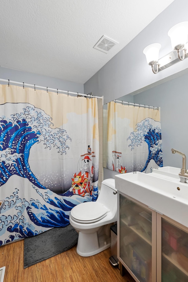 bathroom featuring vanity, toilet, wood-type flooring, and a textured ceiling