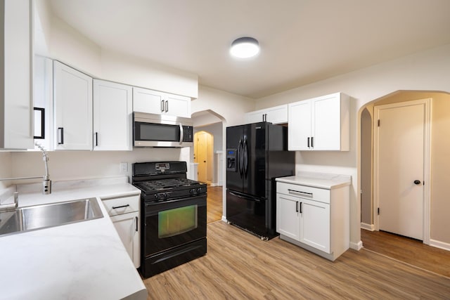 kitchen with black appliances, light hardwood / wood-style floors, white cabinetry, and sink