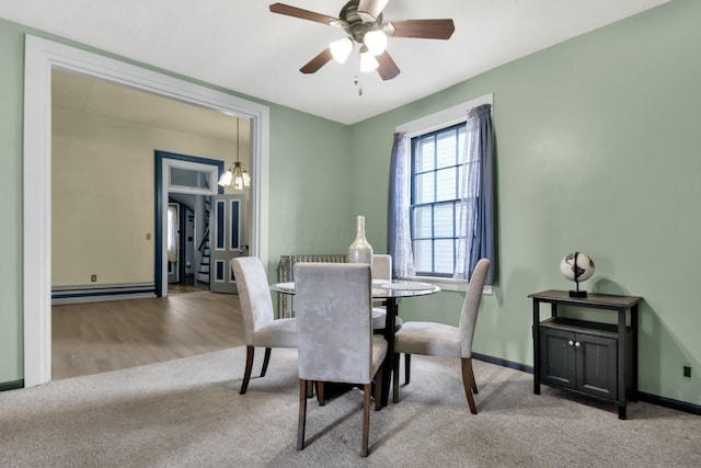 carpeted dining room with ceiling fan with notable chandelier and baseboard heating