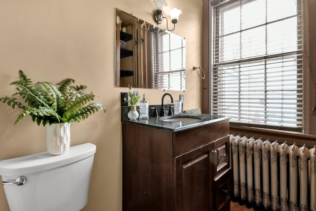 bathroom with vanity, toilet, and radiator heating unit