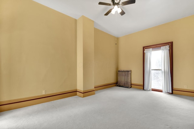 spare room featuring ceiling fan, radiator heating unit, and light carpet