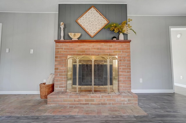 room details with wooden walls, hardwood / wood-style flooring, and a brick fireplace