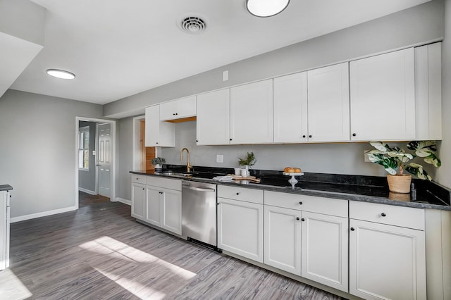 kitchen with dishwasher, sink, dark stone countertops, light wood-type flooring, and white cabinetry