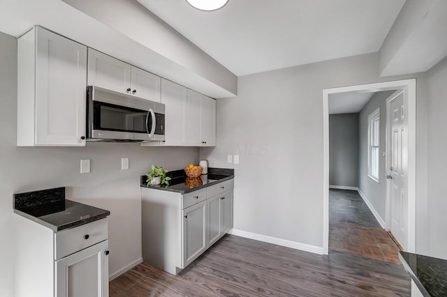 kitchen with dark hardwood / wood-style floors, white cabinetry, and dark stone counters