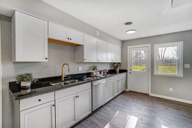 kitchen with stainless steel dishwasher, dark stone counters, sink, light hardwood / wood-style floors, and white cabinetry