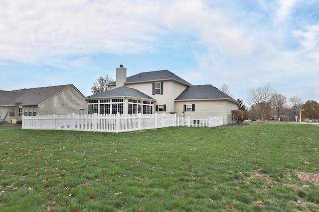 rear view of house featuring a sunroom and a lawn