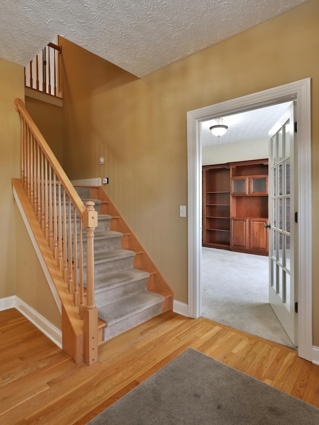 stairs featuring wood-type flooring and a textured ceiling