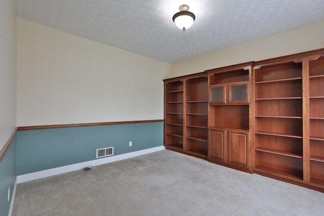 carpeted empty room with a textured ceiling