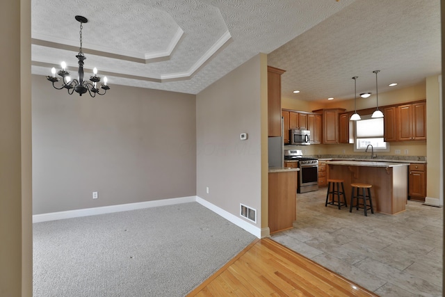 kitchen featuring stainless steel appliances, light hardwood / wood-style flooring, pendant lighting, a textured ceiling, and a kitchen island