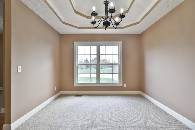 empty room with a chandelier, carpet floors, a tray ceiling, and ornamental molding