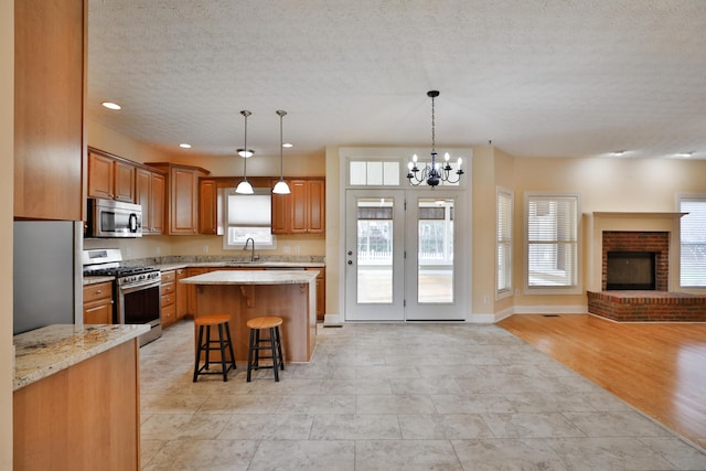 kitchen featuring a breakfast bar, sink, a brick fireplace, light hardwood / wood-style floors, and stainless steel appliances