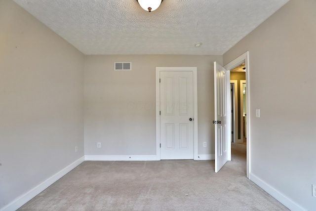 carpeted spare room with a textured ceiling