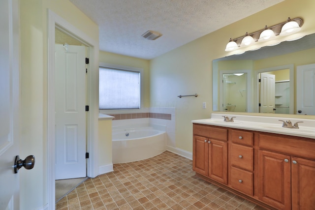 bathroom with a bathing tub, vanity, and a textured ceiling