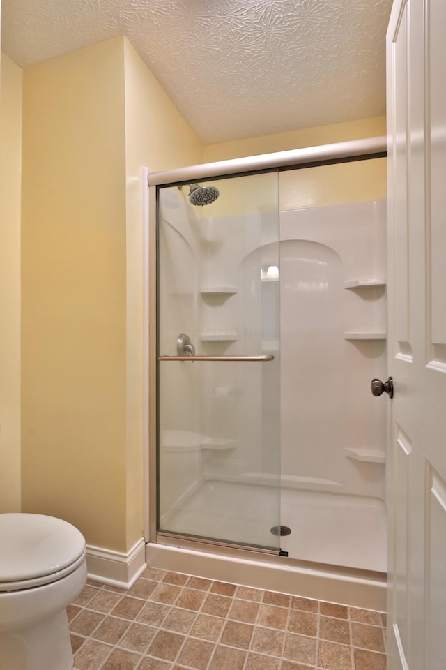 bathroom featuring toilet, a textured ceiling, tile patterned floors, and a shower with door