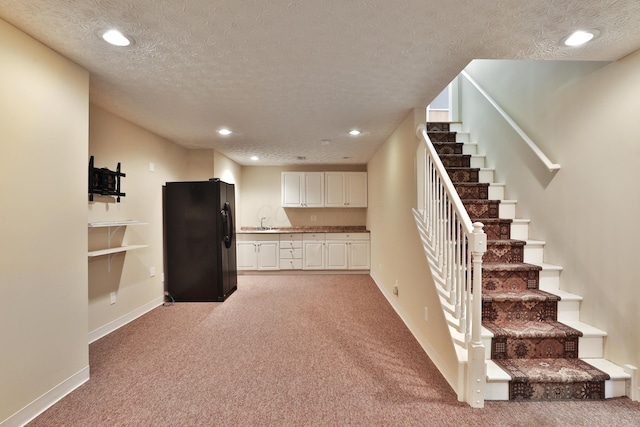 interior space featuring carpet, a textured ceiling, black fridge, and sink